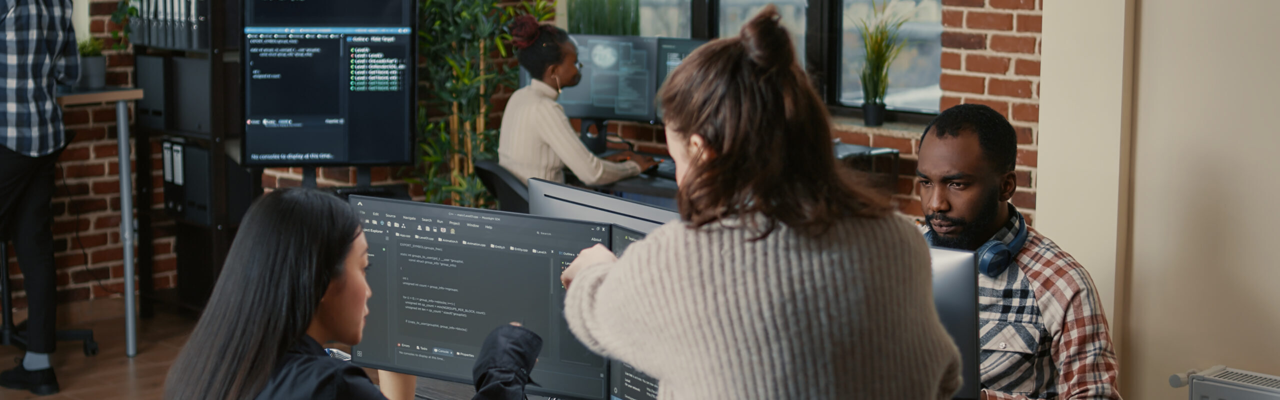 Software programer pointing pencil at source code on computer screen explaining algorithm to coworker standing next to desk. Programmers discussing online cloud computing with team.